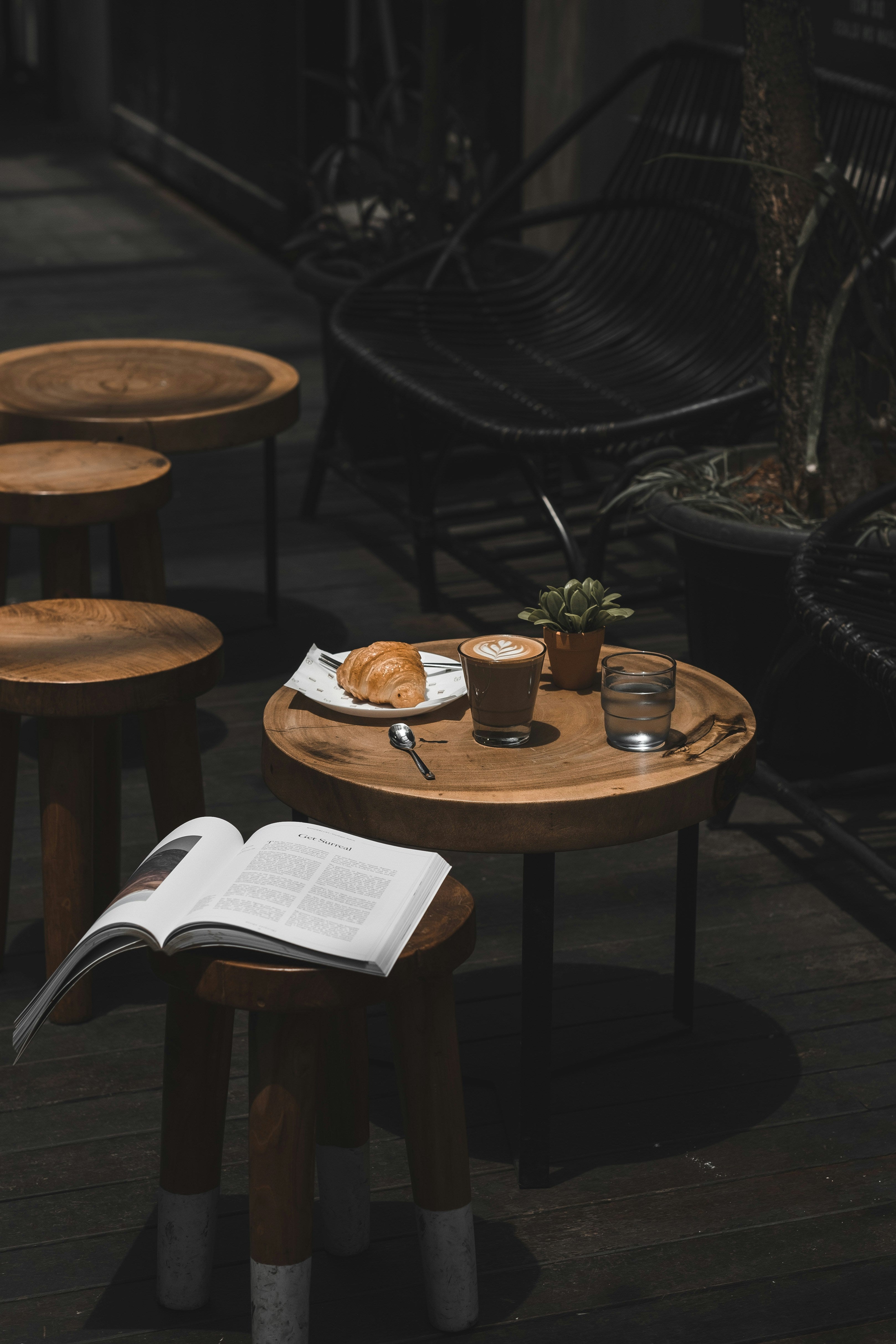 Espresso, Croissant und ein Magazin auf einem Holztisch im Café